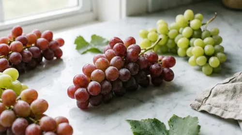 Fresh red and green grapes on a pale marble counter in soft daylight, the fruit behind this grapes nutrition breakdown
