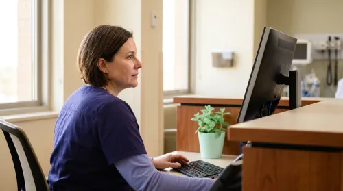 Clinician at a modern workstation reviewing a patient's connected digital health record on a clean screen