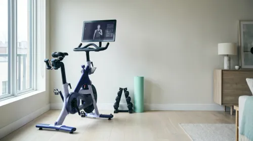 Connected stationary exercise bike with a large screen set up in a bright modern home gym corner