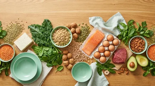 Wooden table split into plant proteins on one side and animal proteins on the other, vegan versus paleo